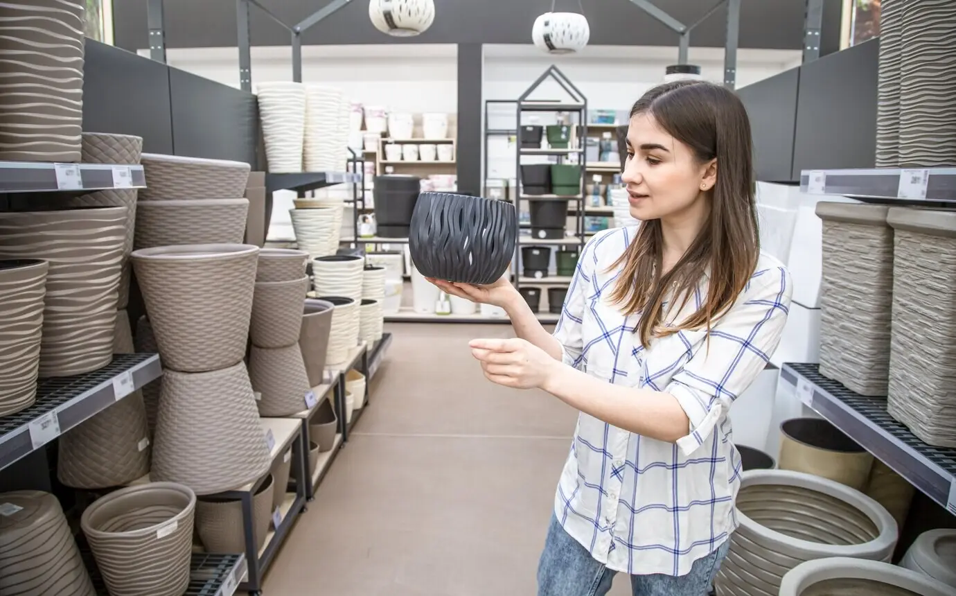 Eine schöne junge Frau sucht in einem Blumenladen einen Blumentopf aus.